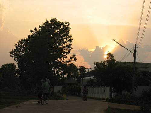 Sun setting on road with children on bikes in Mae Pa